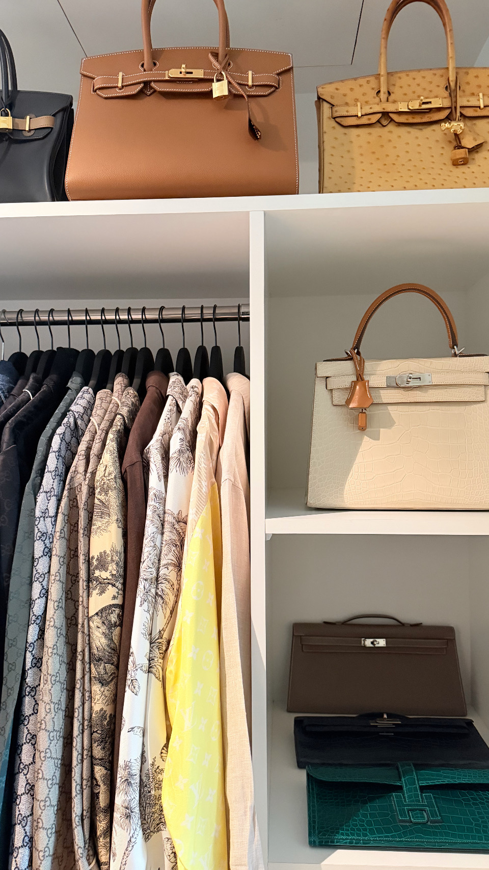 Birkin and Kelly bags beside a rail of silk shirts
