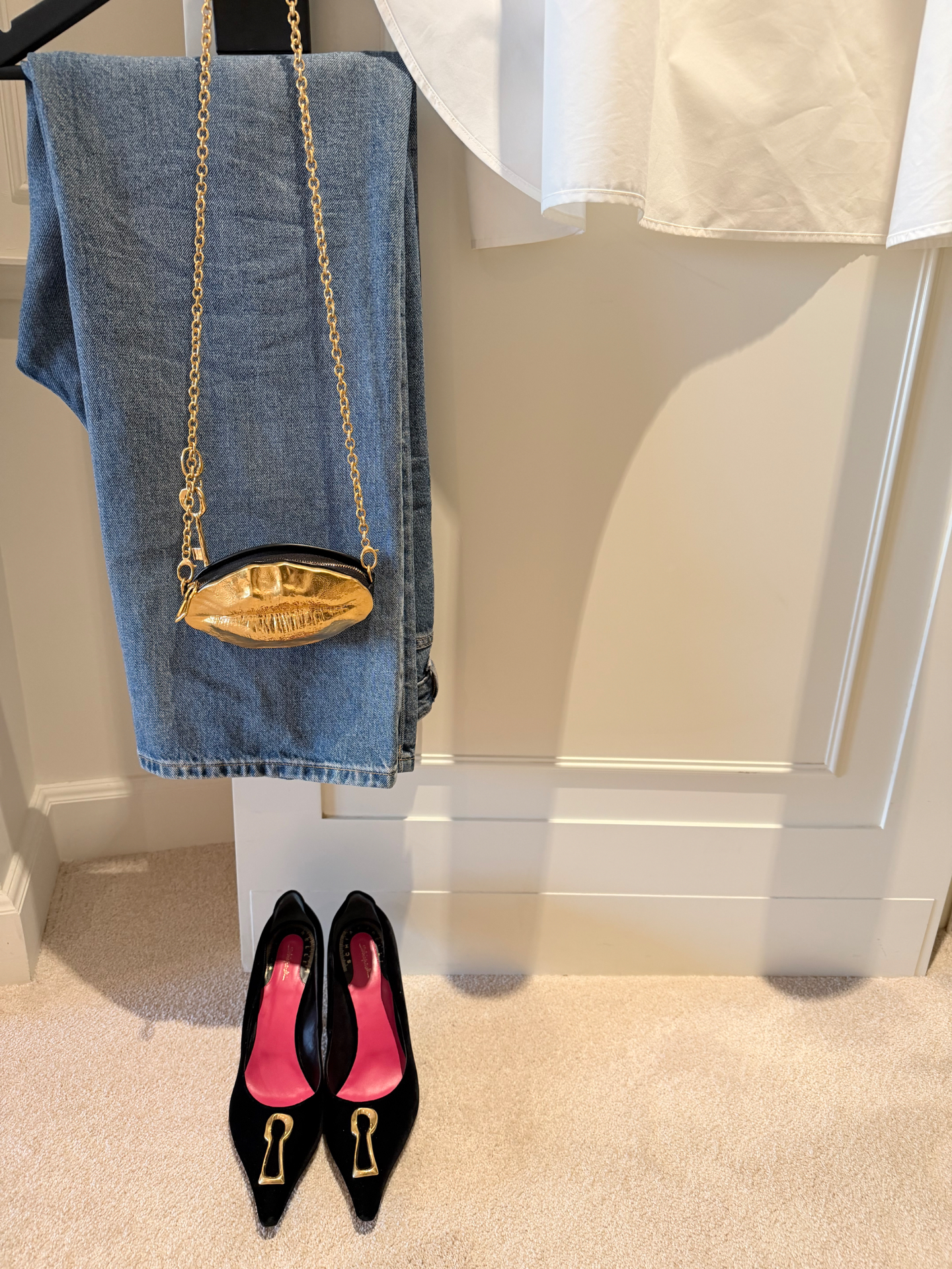 An outfit styled with denim, a gold bag and black heels