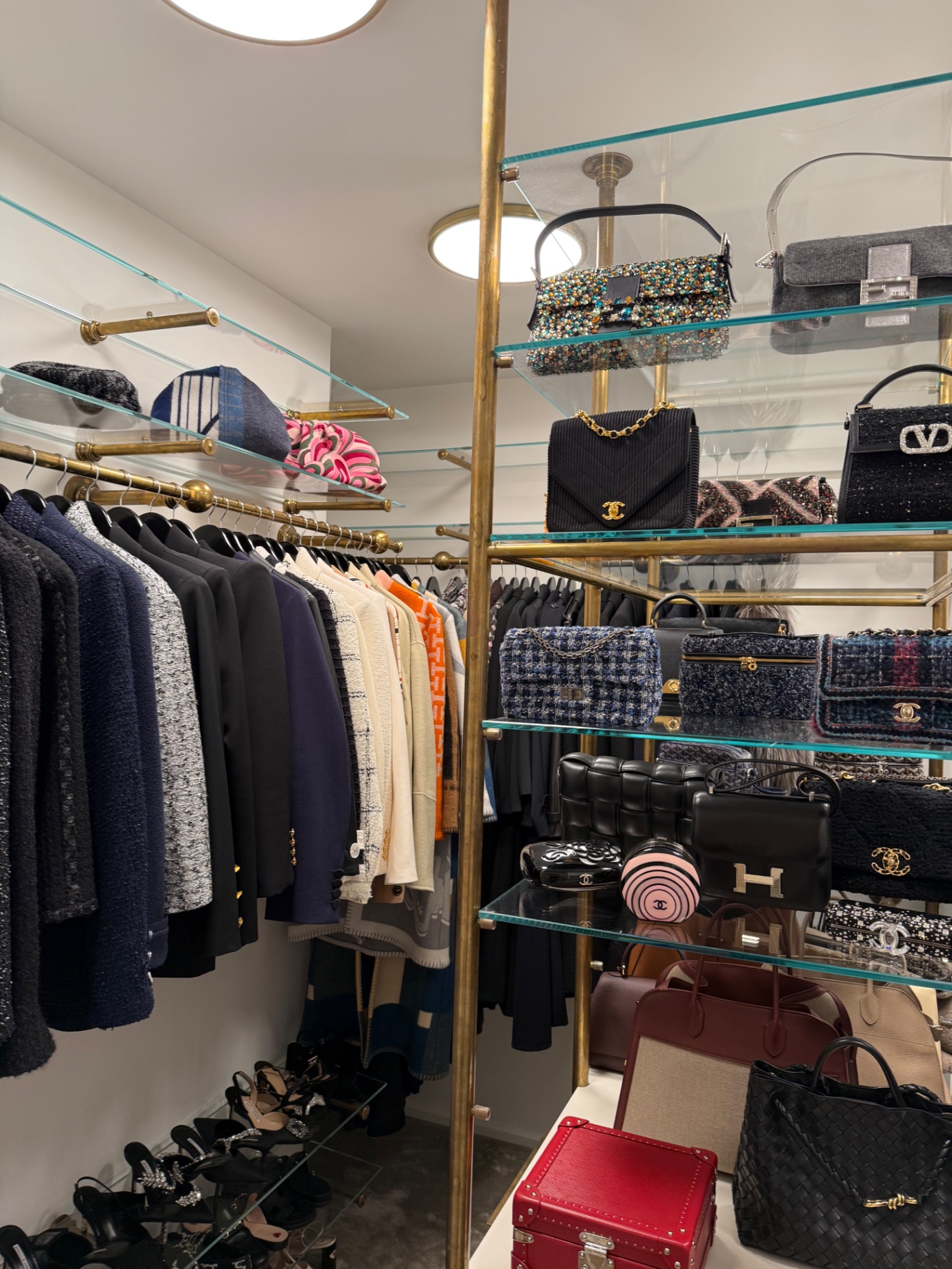Tailoring and Chanel handbags on brass and glass shelving